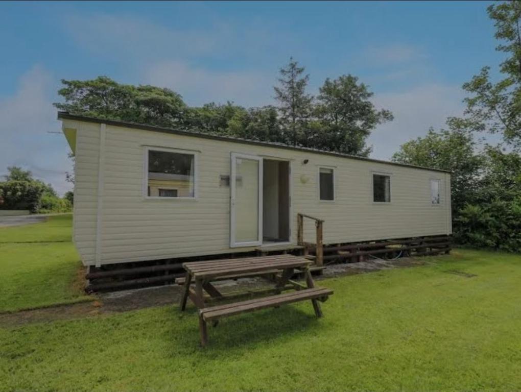 a tiny house with a picnic table in front of it at Caravan 3 - Blackmoor farm near Tenby in Ludchurch