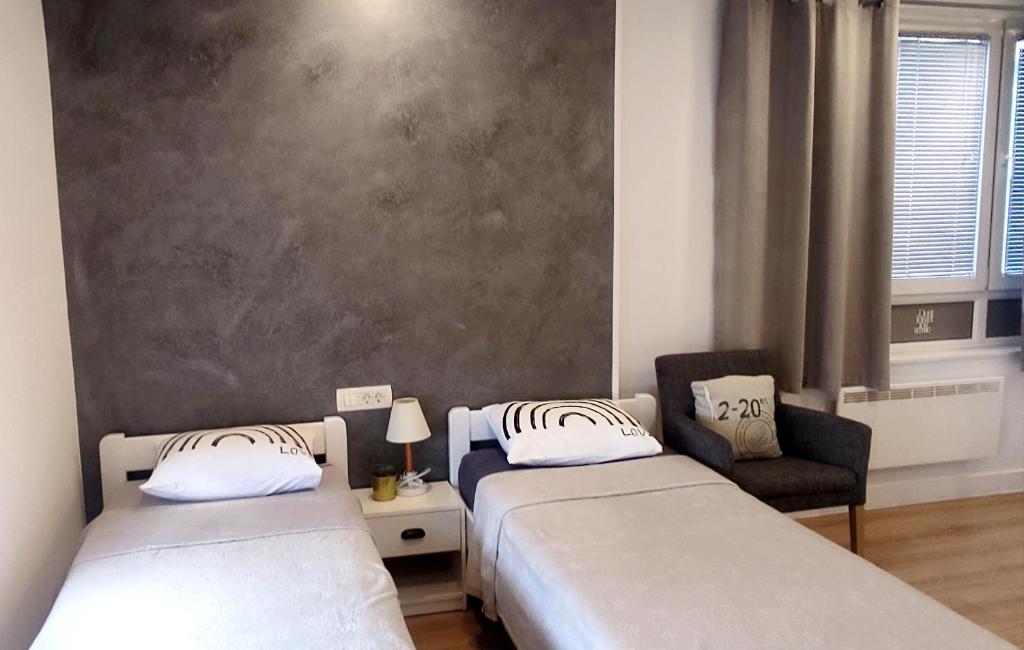 una habitación con dos camas y una silla en Lea Studios, en Zagreb