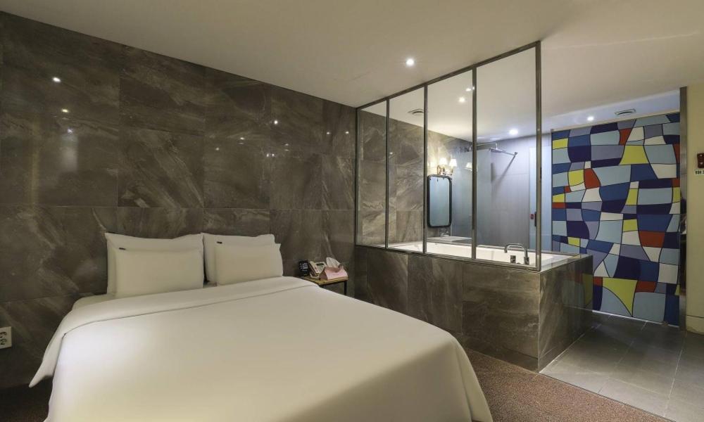 a bedroom with a white bed and a bath tub at Hotel H2 in Ulsan
