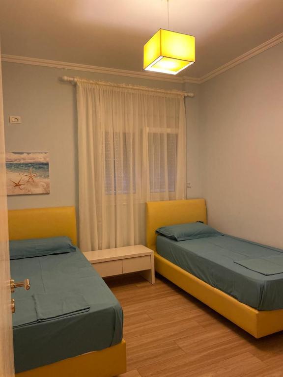 two beds sitting in a room with a window at Apartment in Primavera Residence in Fushë-Draç
