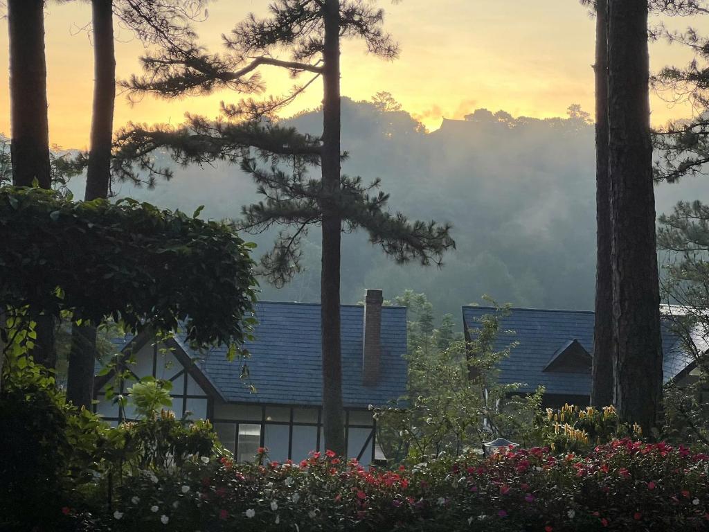 ein Haus mit blauem Dach und Bäumen und Blumen in der Unterkunft Lan Anh Villas Resort in Da Lat
