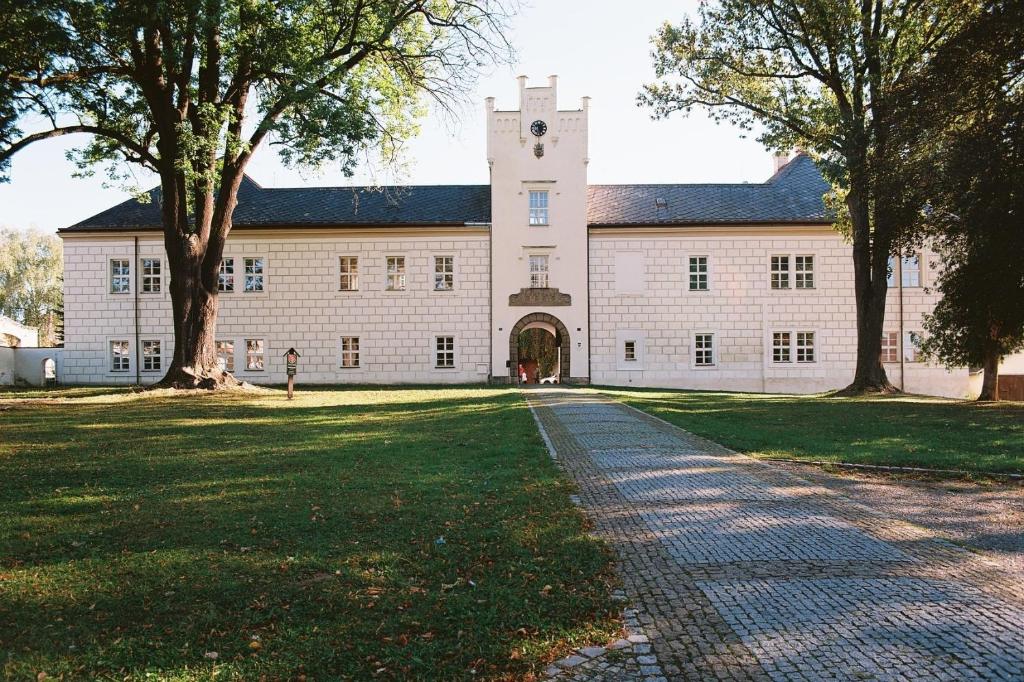 a large white building with a clock tower at Zámek Spálené Poříčí in Spálené Poříčí