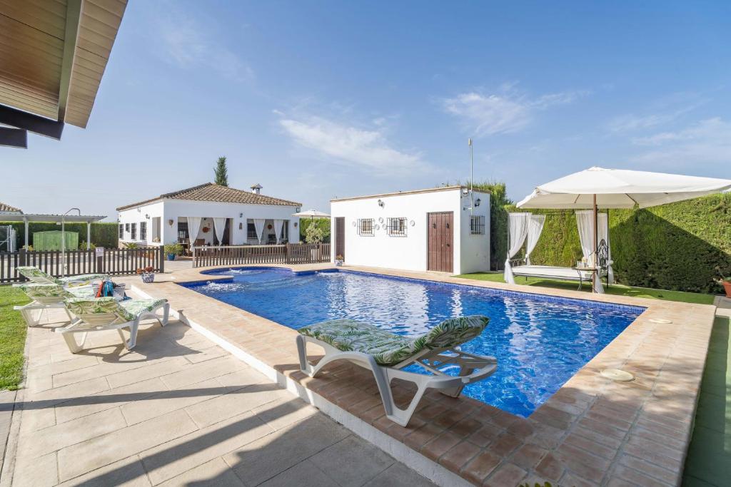 una piscina con due lettini e un ombrellone di Casa rural Buhaira a La Puebla de Cazalla