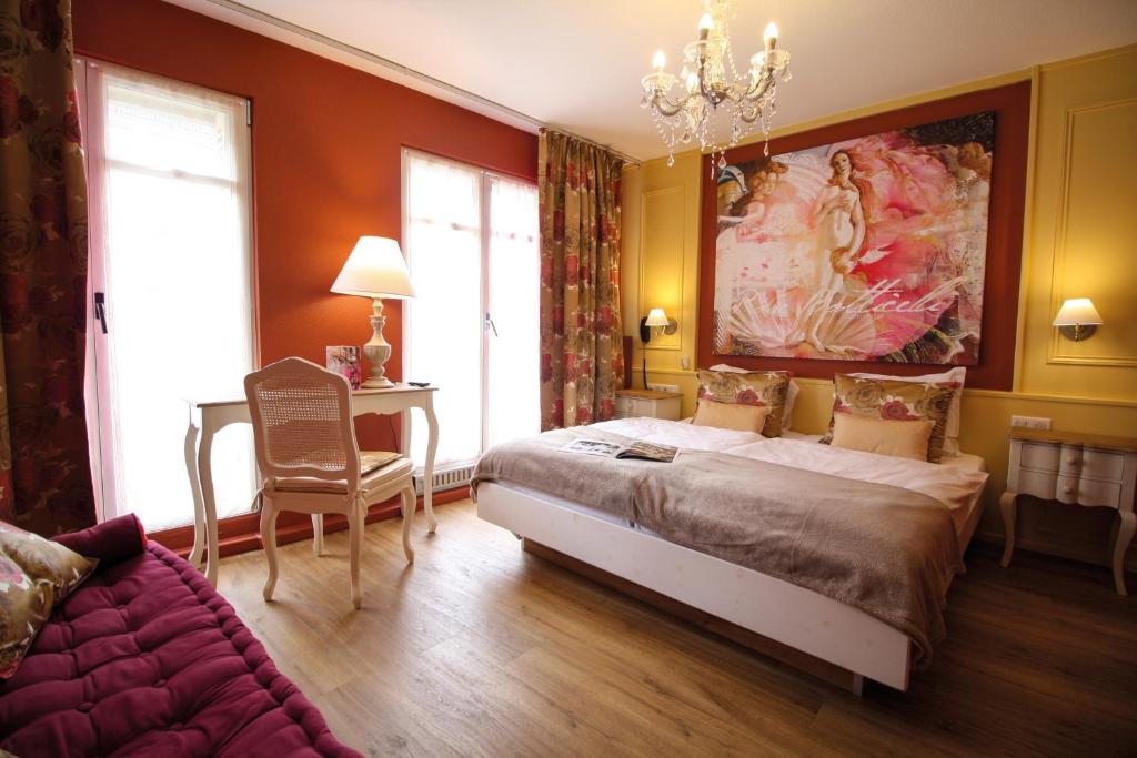 a bedroom with a bed, a desk and a painting on the wall at Hotel Roses in Strasbourg