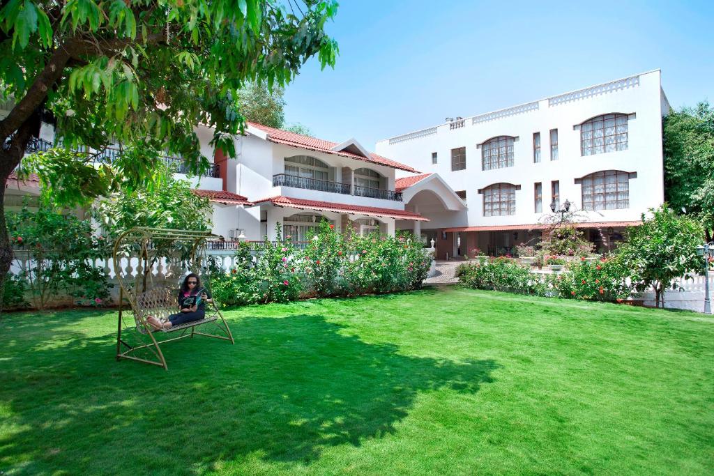 a woman sitting in a chair in the yard of a house at Villa San Lawrenz in Lonavala