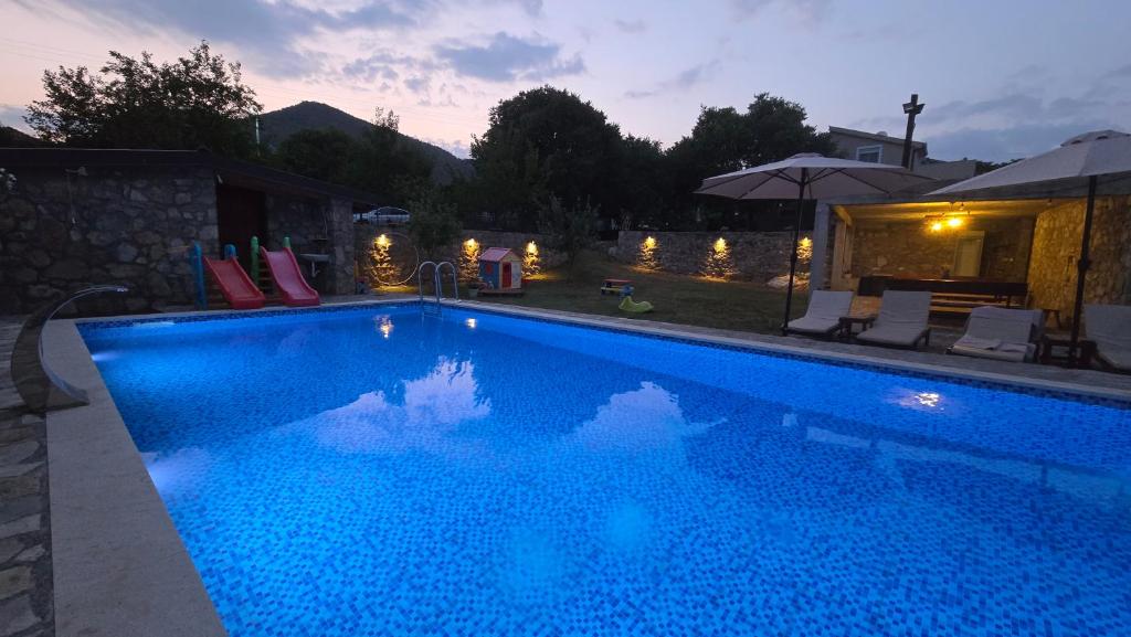 a blue swimming pool with lights in a backyard at Wildstone Krusi - Pool & Apartments 1 in Podgorica