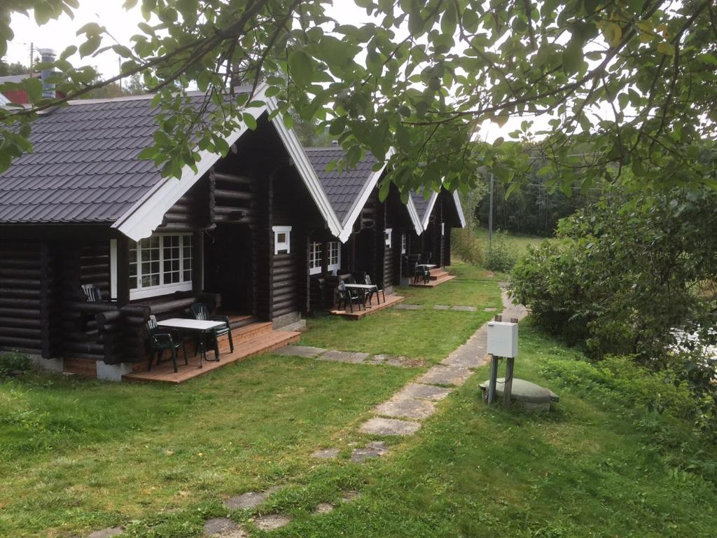 uma cabana de madeira com um alpendre e um quintal em Fosheim Hytter em Ron