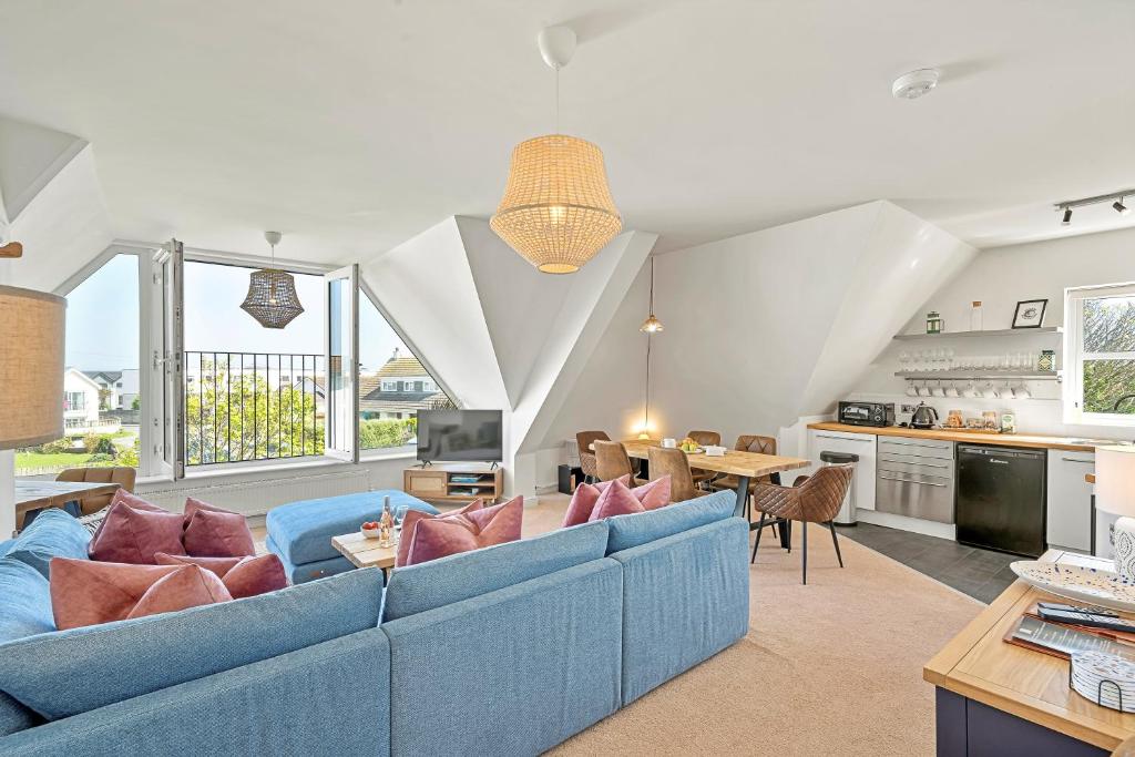 a living room with a blue couch and a kitchen at Pentire Point - Coastal Penthouse, Beaches, River & Restaurants All Within Short Walk in Newquay