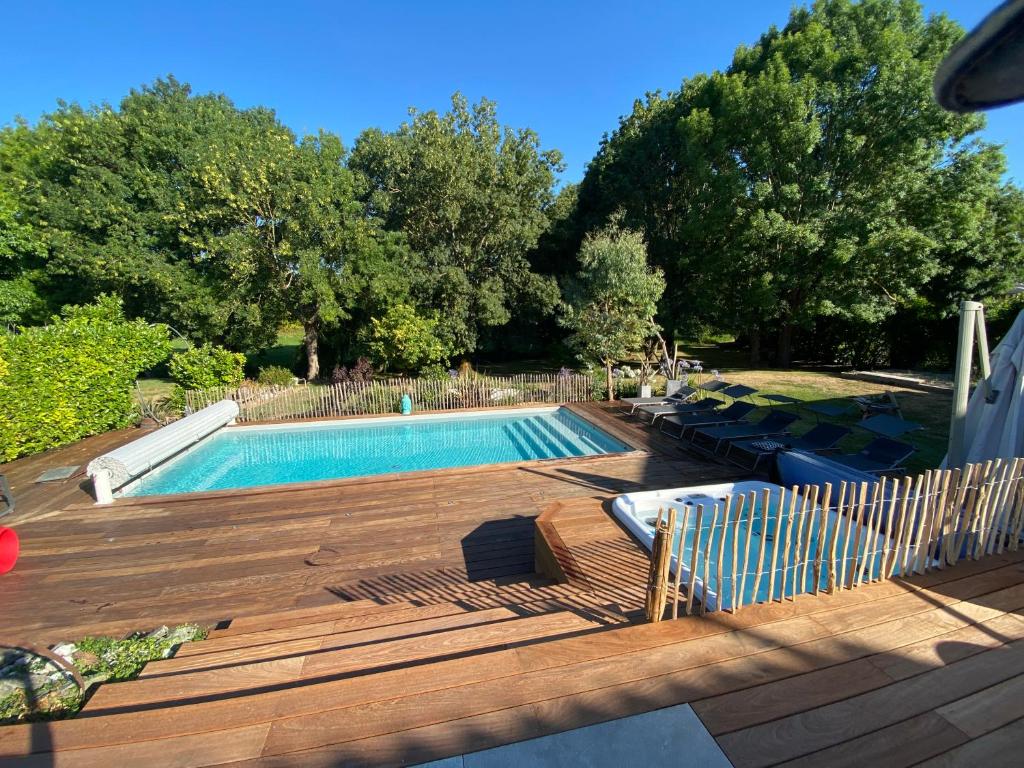 - une piscine avec une terrasse en bois à côté dans l'établissement Villa Whaou 5*, piscine chauffée, jacuzzi, à Sémussac