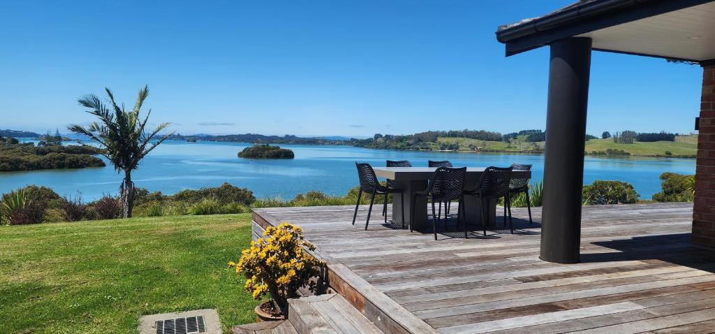 a deck with a table and chairs and a view of a lake at Piwakawaka Lodge Kerikeri - Incredible waterfront views in Kerikeri