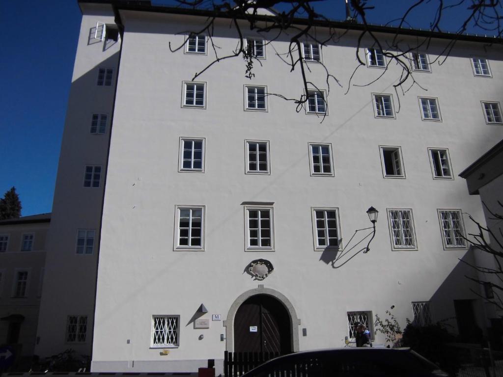 ein weißes Gebäude mit einer Uhr auf der Seite in der Unterkunft Institut St.Sebastian in Salzburg