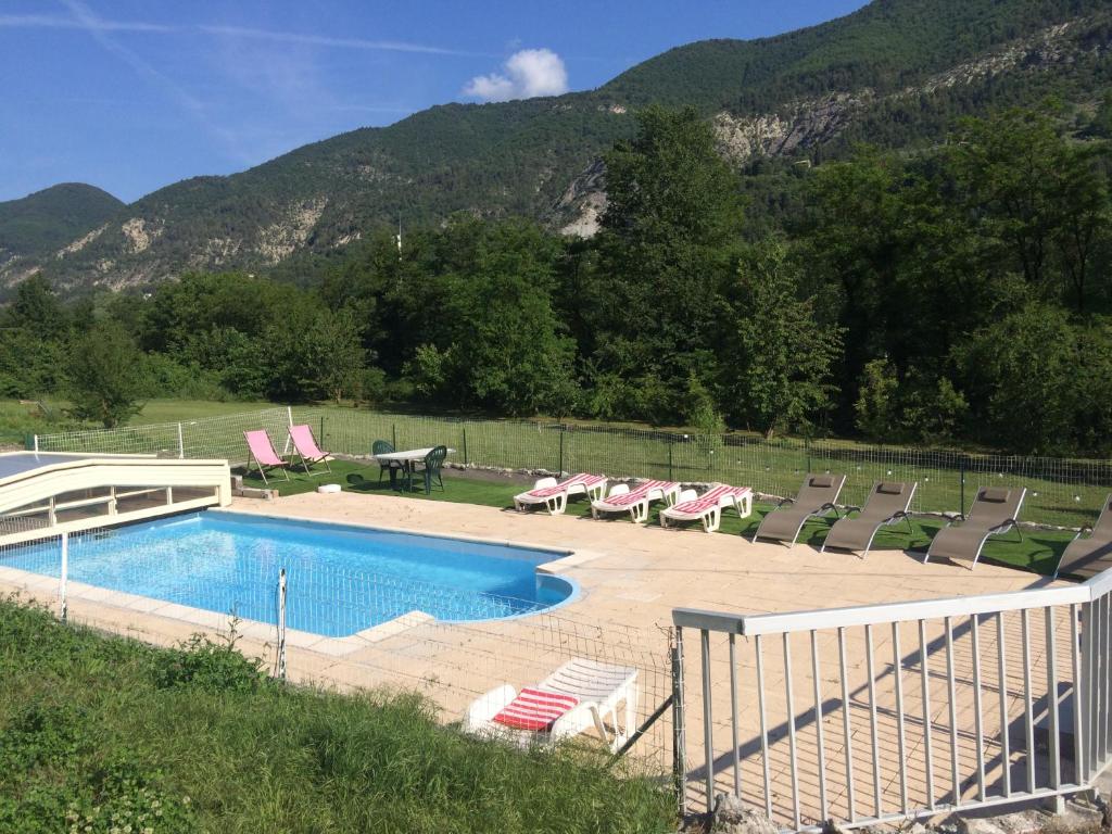 a swimming pool with chairs and a table and a picnic table at Les 2 Alpes in Puget-Théniers