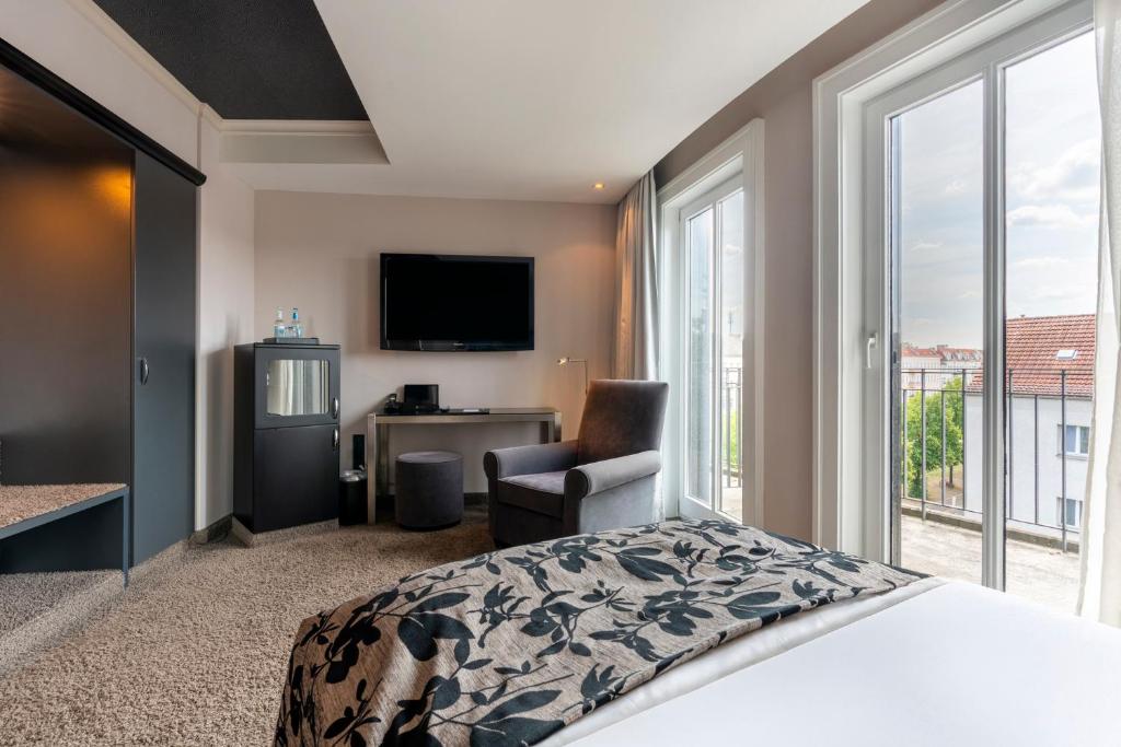 a bedroom with a bed and a tv and a chair at Hotel NEWBERLIN in Berlin