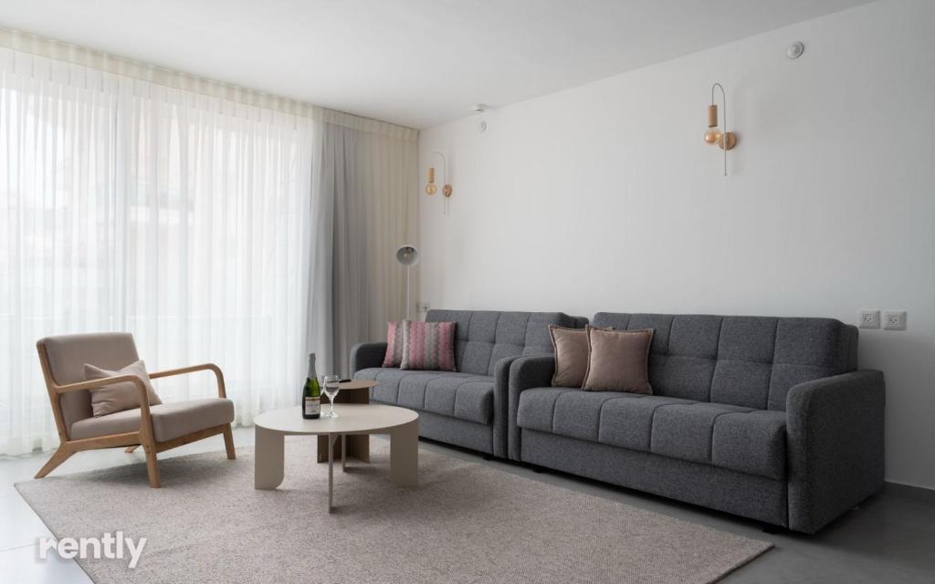 ein Wohnzimmer mit einer Couch und einem Tisch und einem Stuhl in der Unterkunft Luxury Apartments And Studios At Sea Side By Rently in Eilat