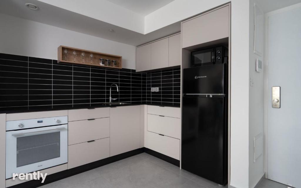 eine Küche mit weißen Schränken und einem schwarzen Kühlschrank in der Unterkunft Luxury Apartments And Studios At Sea Side By Rently in Eilat