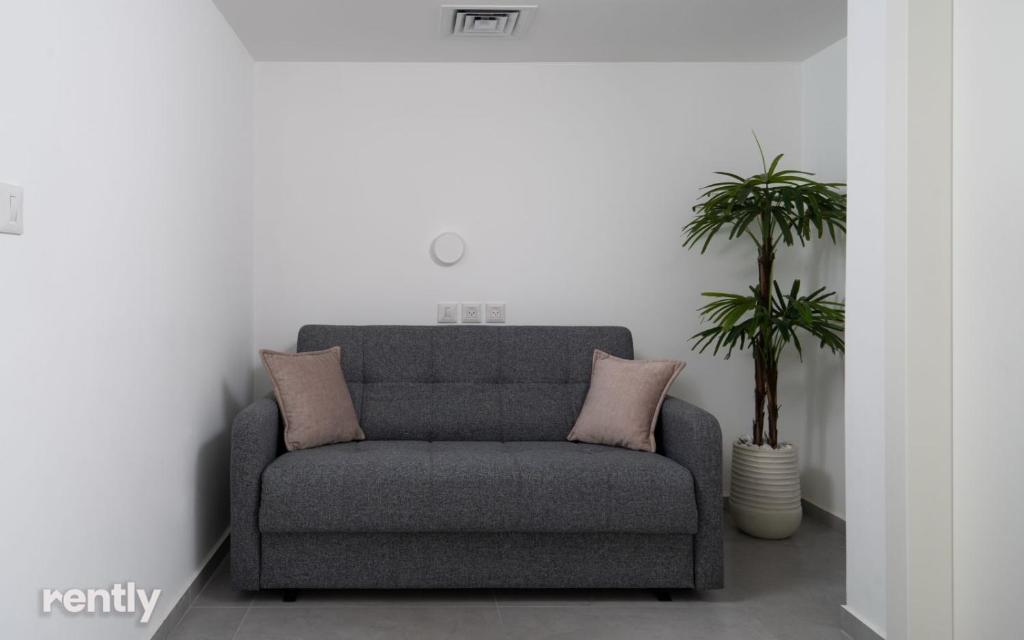 einen grauen Stuhl in einem Raum mit Topfpflanze in der Unterkunft Luxury Apartments And Studios At Sea Side By Rently in Eilat