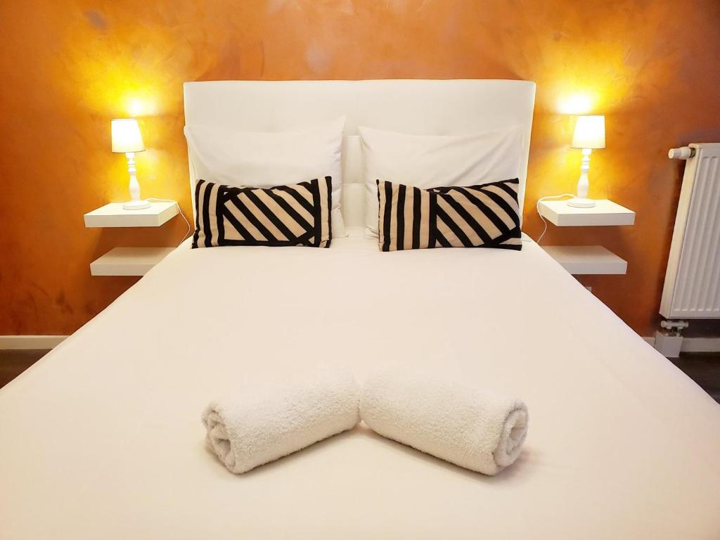 une chambre avec un lit blanc et deux lampes dans l'établissement Le Petit Versailles, à Franconville