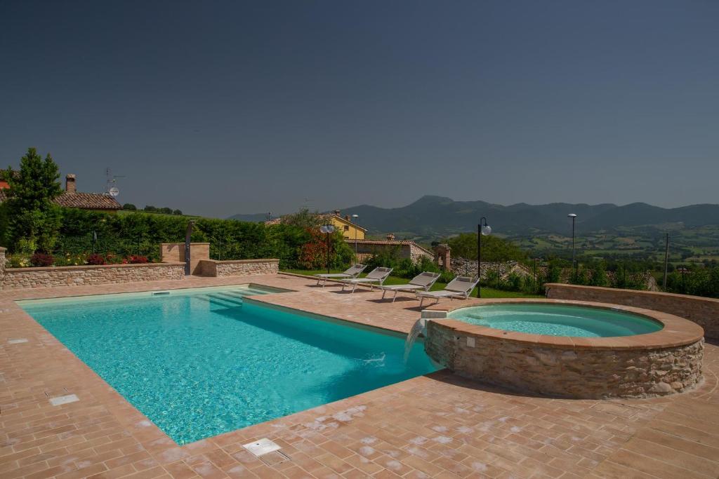 - une piscine avec 2 chaises longues à côté dans l'établissement Il Casato, à Castelraimondo