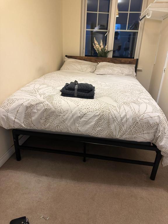 a bed in a bedroom with a black bag on it at Little flat at the top in West Bromwich