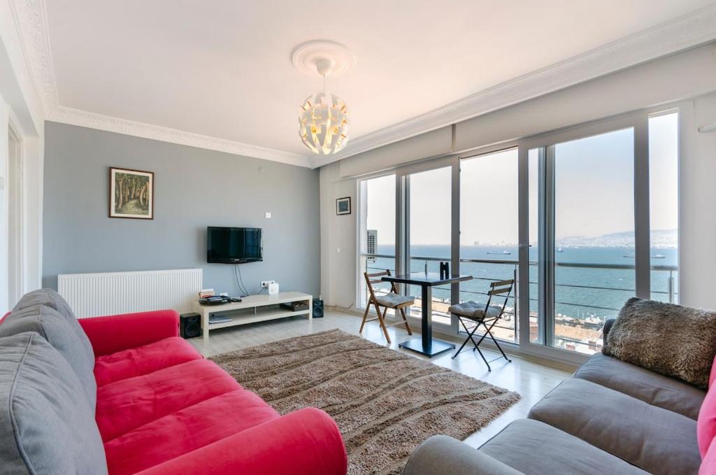 un salon avec un canapé rouge et une table dans l'établissement Windows On The Bay - izmir, à Konak