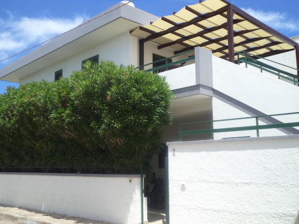 una casa bianca con un albero davanti di Casa del Marinaio 150 mt spiaggia Marangi a San Foca