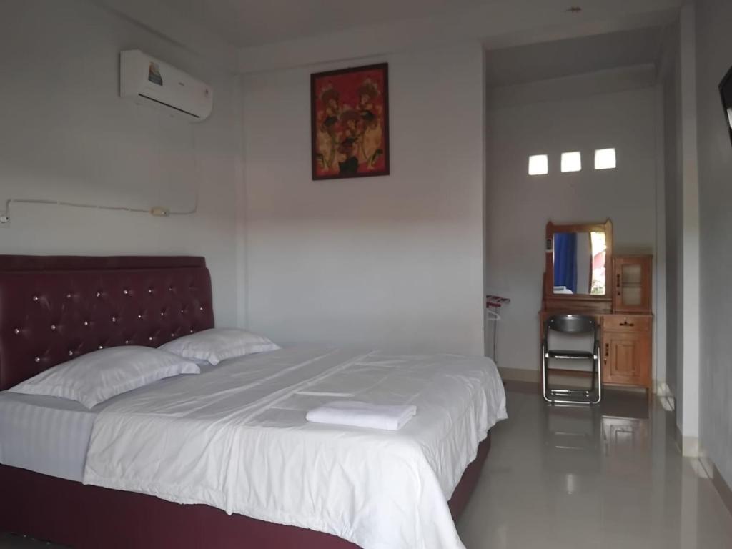 a bedroom with a large bed with white sheets at Hotel Tropicana in Tentena