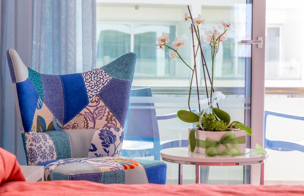 a living room with a chair and a table with a plant at Nicholas Color Hotel in Ayia Napa