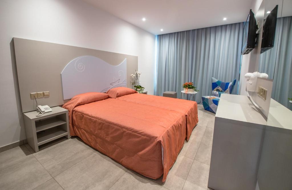 a bedroom with a bed with an orange bedspread at Nicholas Color Hotel in Ayia Napa