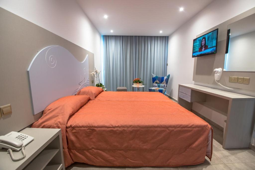 a hotel room with a bed with an orange bedspread at Nicholas Color Hotel in Ayia Napa