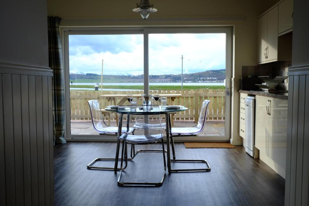 a kitchen with a table and chairs in front of a window at Otter Cottage in Inverness