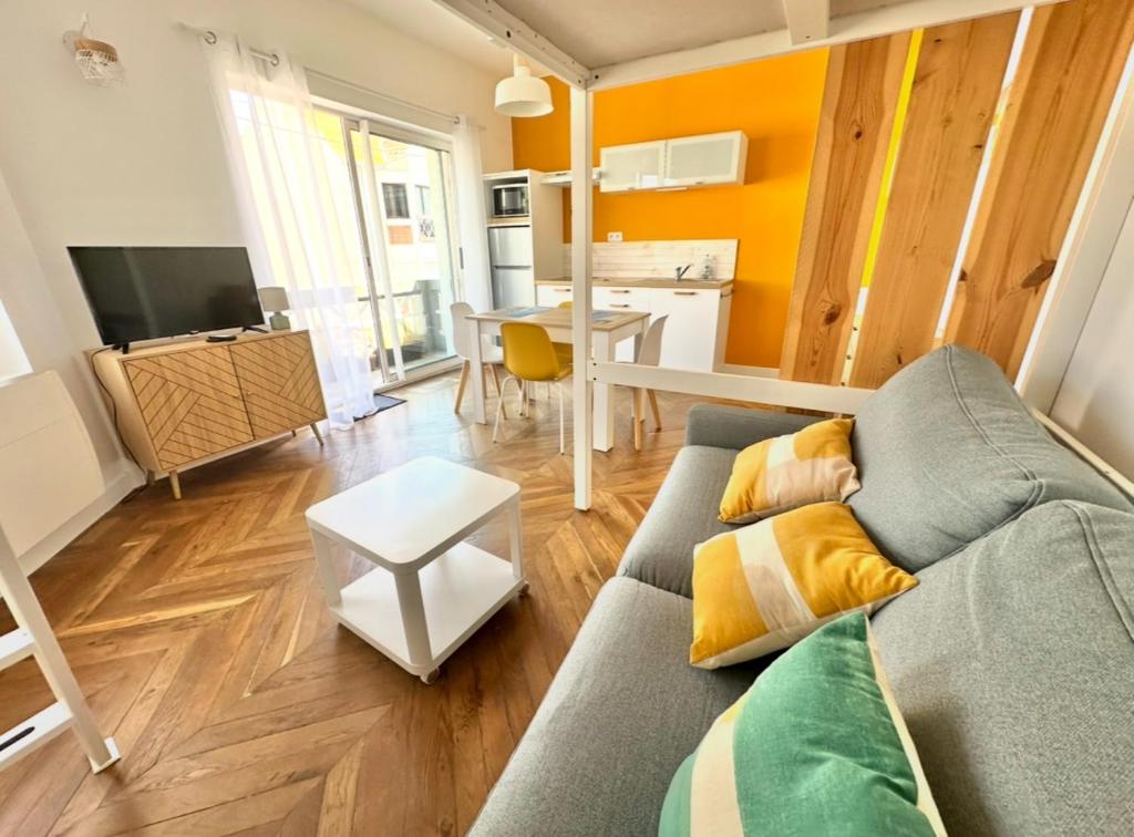 een woonkamer met een bank en een tafel bij Grand Studio JAUNE pour 4 pers à deux pas de la plage de Berck in Berck-sur-Mer