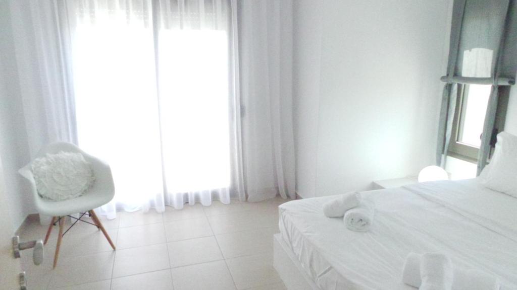 a bedroom with a bed and a chair and a window at Niovi Boutique Apartments in Afitos