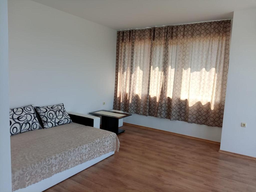 a bedroom with a bed and a window with curtains at Апартаменты за гости Гавань in Byala