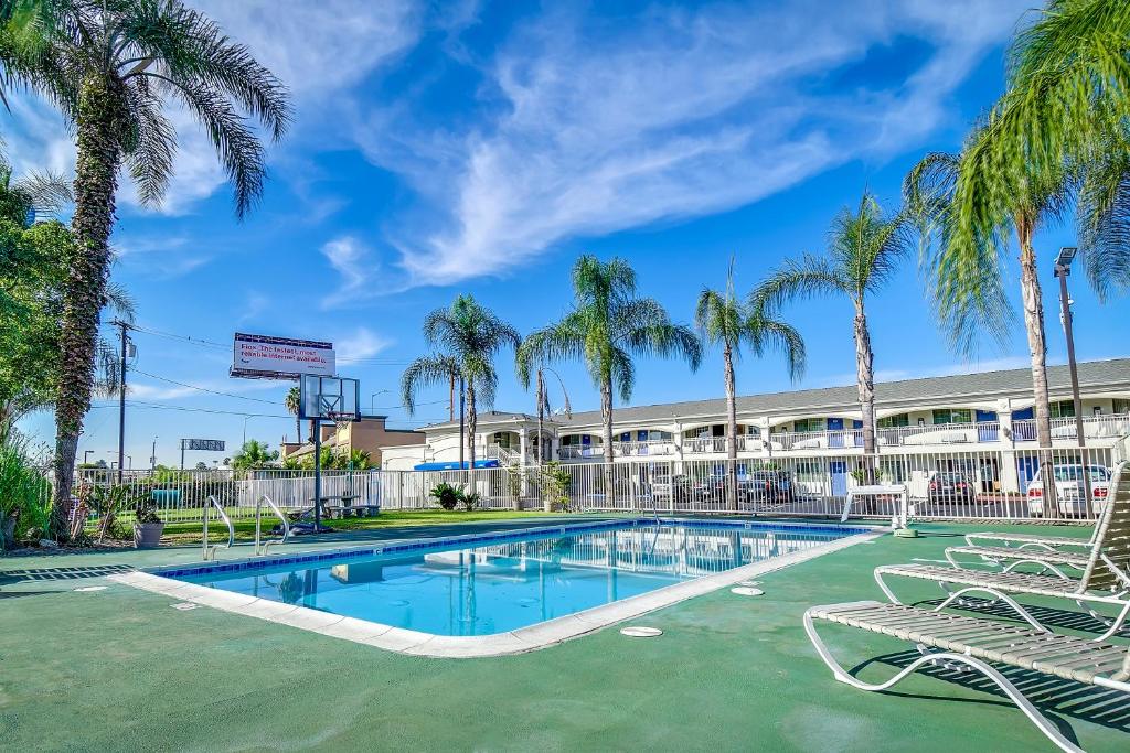 a swimming pool with palm trees in front of a building at Motel 6 Garden Grove in Anaheim