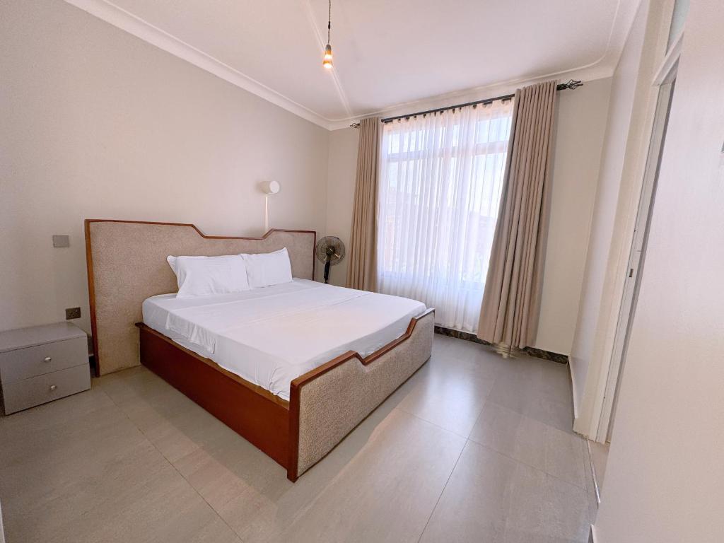 a bedroom with a bed and a large window at Spacious 1Bedroom Apartment in Muyenga off Bukasa Road in Kampala
