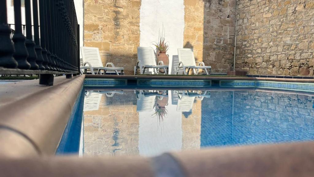 a swimming pool with white chairs and a group at Hotel Rosaleda Don Pedro in Úbeda