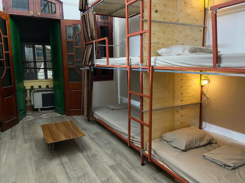 une chambre avec trois lits superposés et une table dans l'établissement DA Travel Home - Hanoi Hostel, à Hanoï