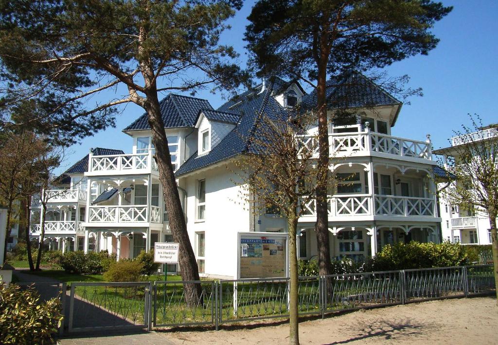 a large white house with a fence in front of it at Strandläufer im Haus Strelasund in Binz