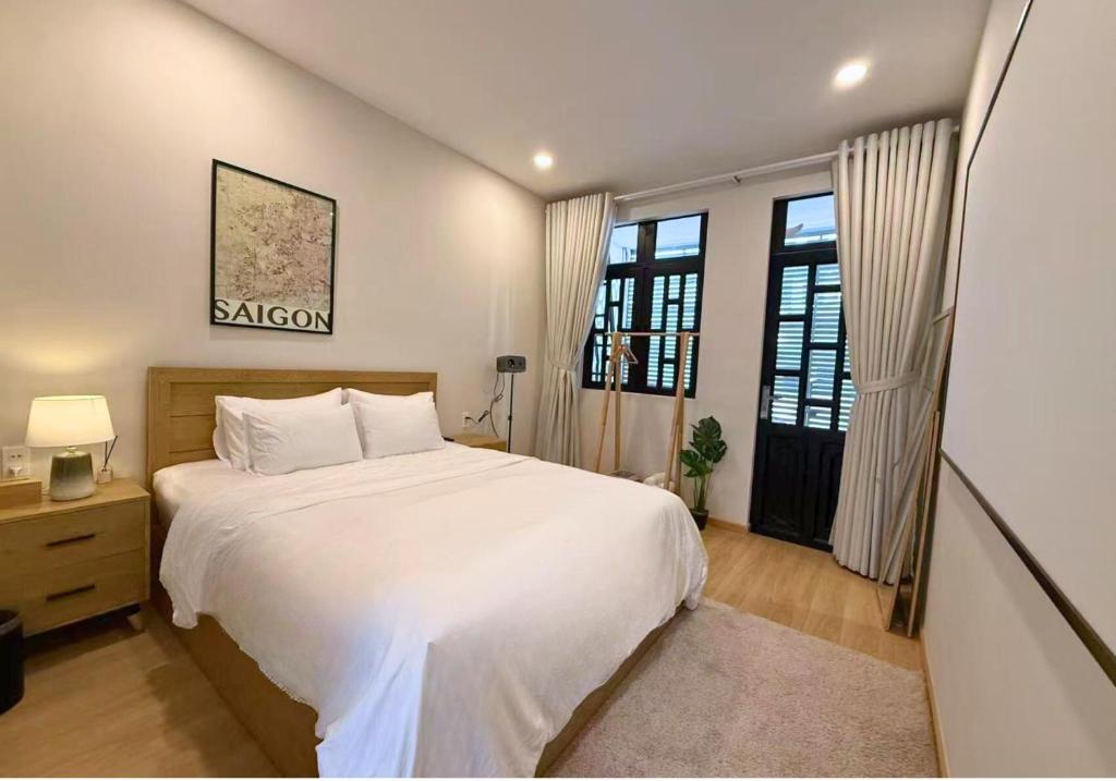 a bedroom with a large white bed and windows at Tranquil City Center Wabi Sabi 3BR Townhouse in D1 in Ho Chi Minh City