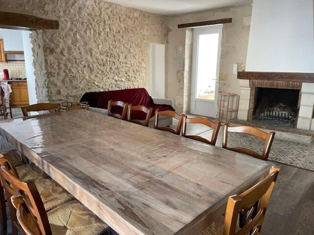 un grande tavolo in legno in un soggiorno con camino di Saint Pierre de Maillé 86260 Maison a Saint-Pierre-de-Maillé