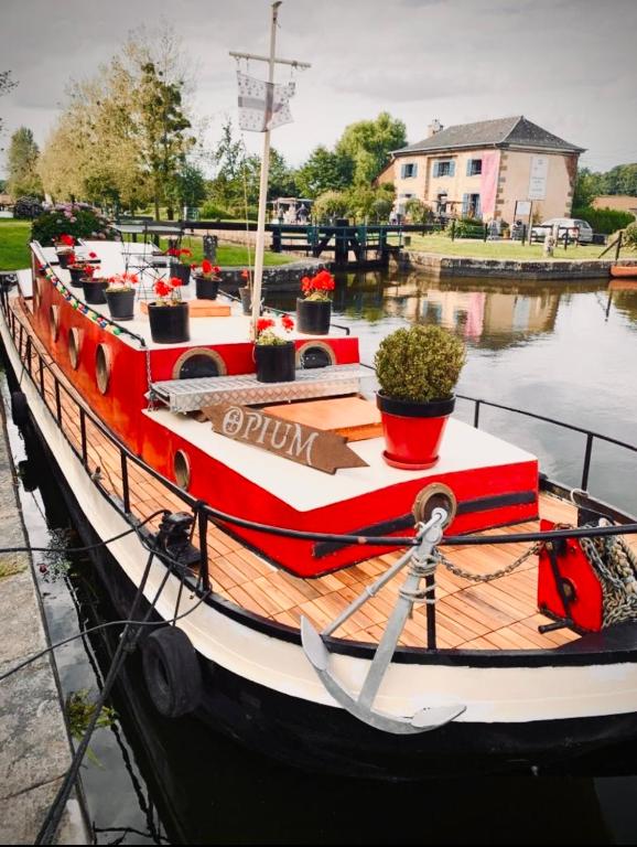 un bateau rouge est amarré dans l'eau dans l'établissement Très jolie péniche à louer, à Hédé