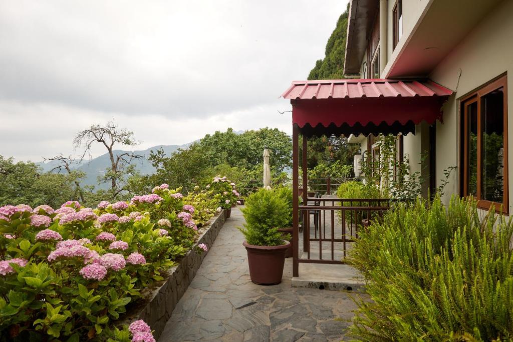 a porch of a house with flowers and plants at May Cottage By Rokeby Villas in Mussoorie