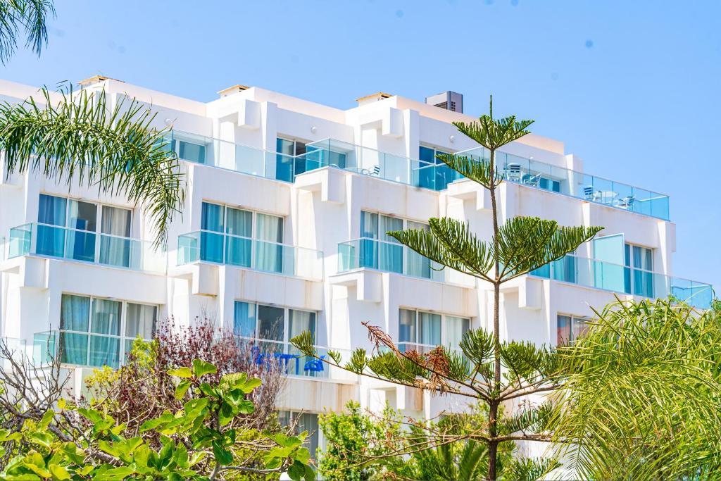 a white building with palm trees in front of it at Hotel Rais in Alger