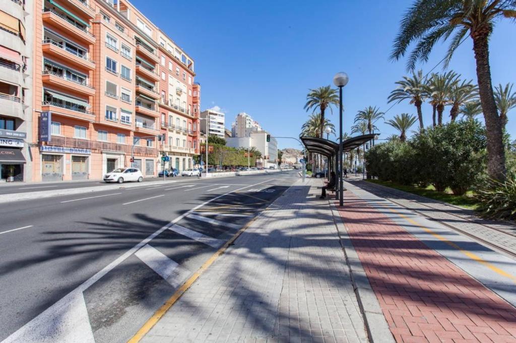 una calle con palmeras al lado de la carretera en Apartamentos Bahía Alicante, en Alicante