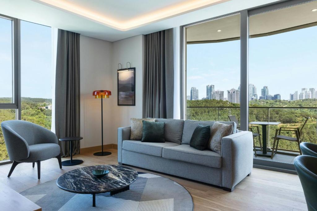 Una sala de estar con un sofá y sillas y ventanas. en Marriott Executive Apartments Istanbul Investvadi, en Estambul