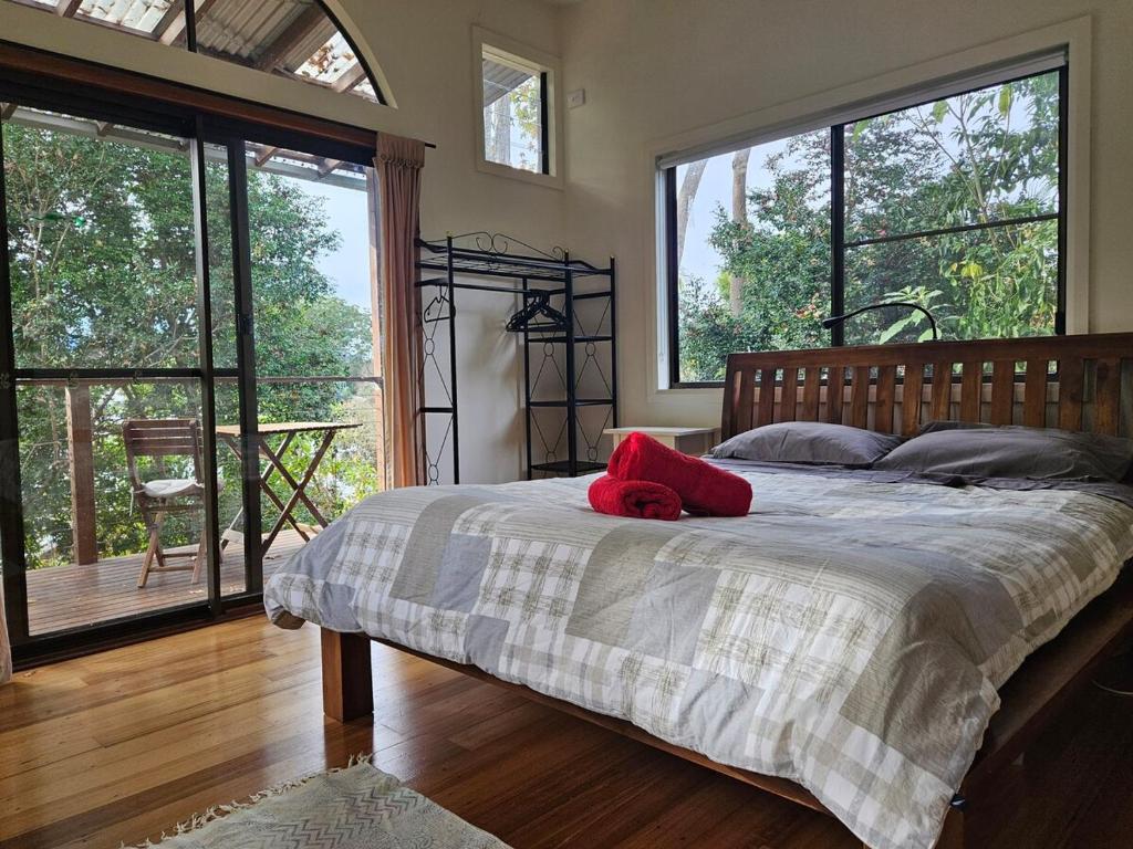 1 dormitorio con 1 cama con 2 almohadas rojas en Bellingen - Hilltop Garden Studio, en Bellingen