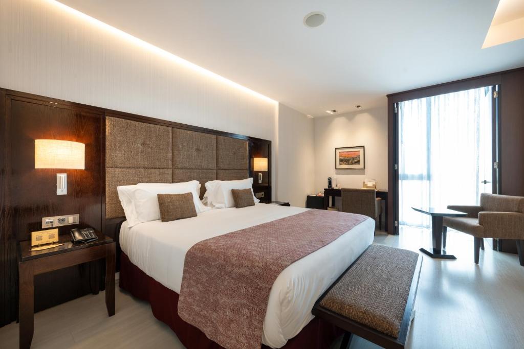 a hotel room with a large bed and a chair at Hotel Diagonal Plaza in Zaragoza