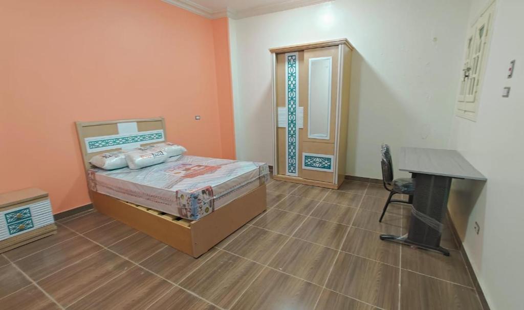 a bedroom with a bed and a desk and a table at Nile Pearl Apartment in Mît Khamîs