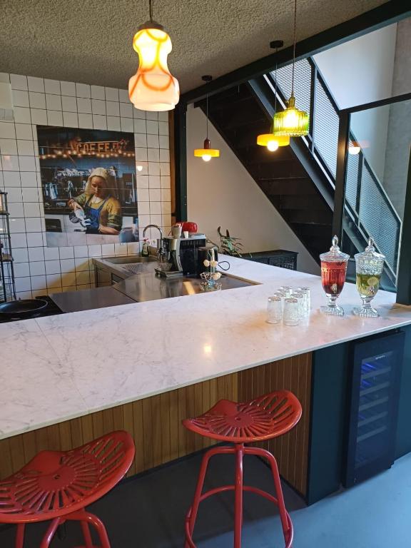 a kitchen with two red stools at a counter at B&B Boudevino in Lekkerkerk