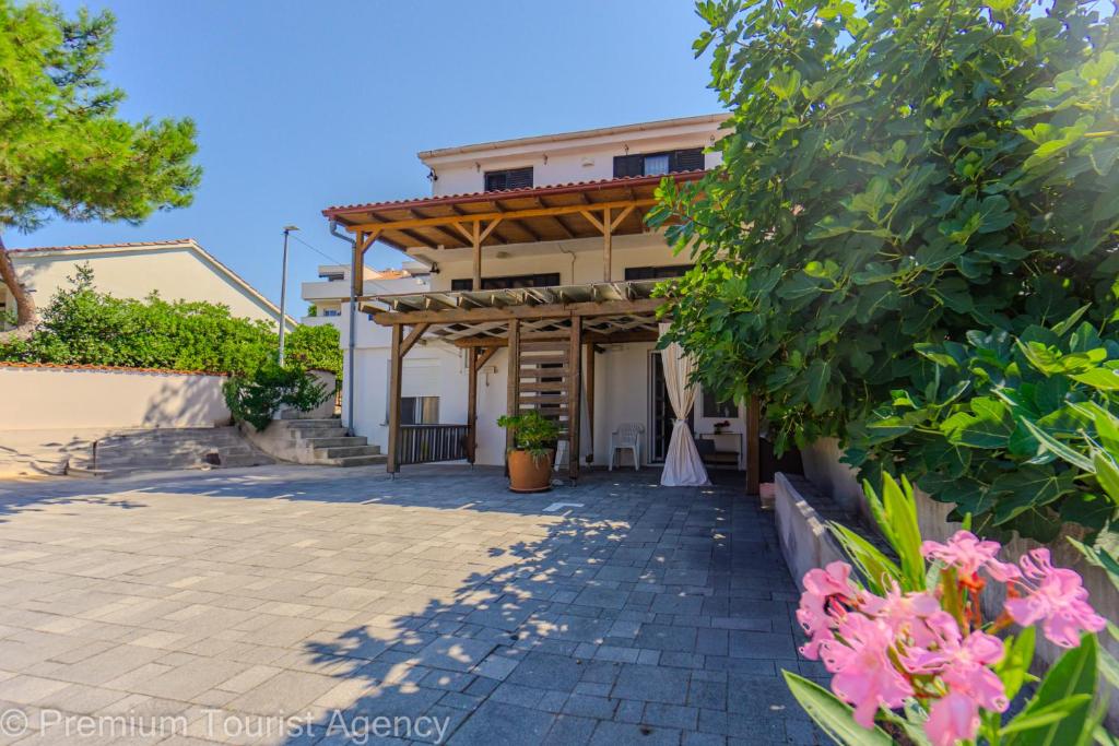 a house with a patio and flowers in front of it at Gato in Novalja